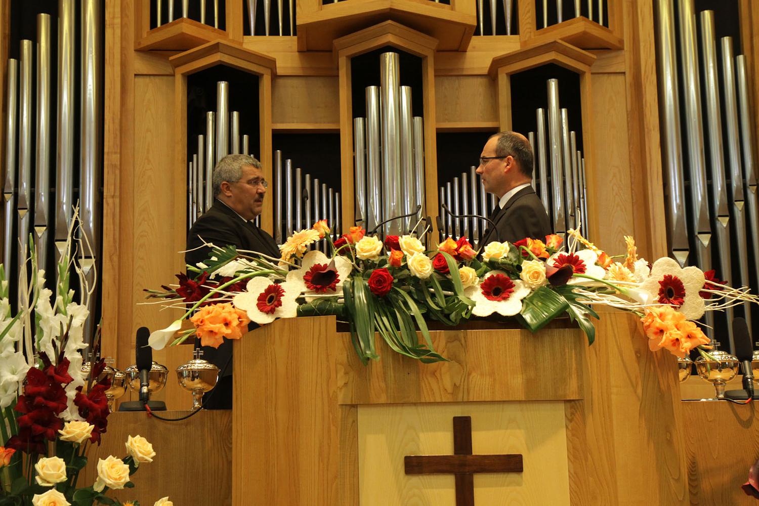Stammapostel Schneider ordiniert den neuen Apostel Arèse (links)